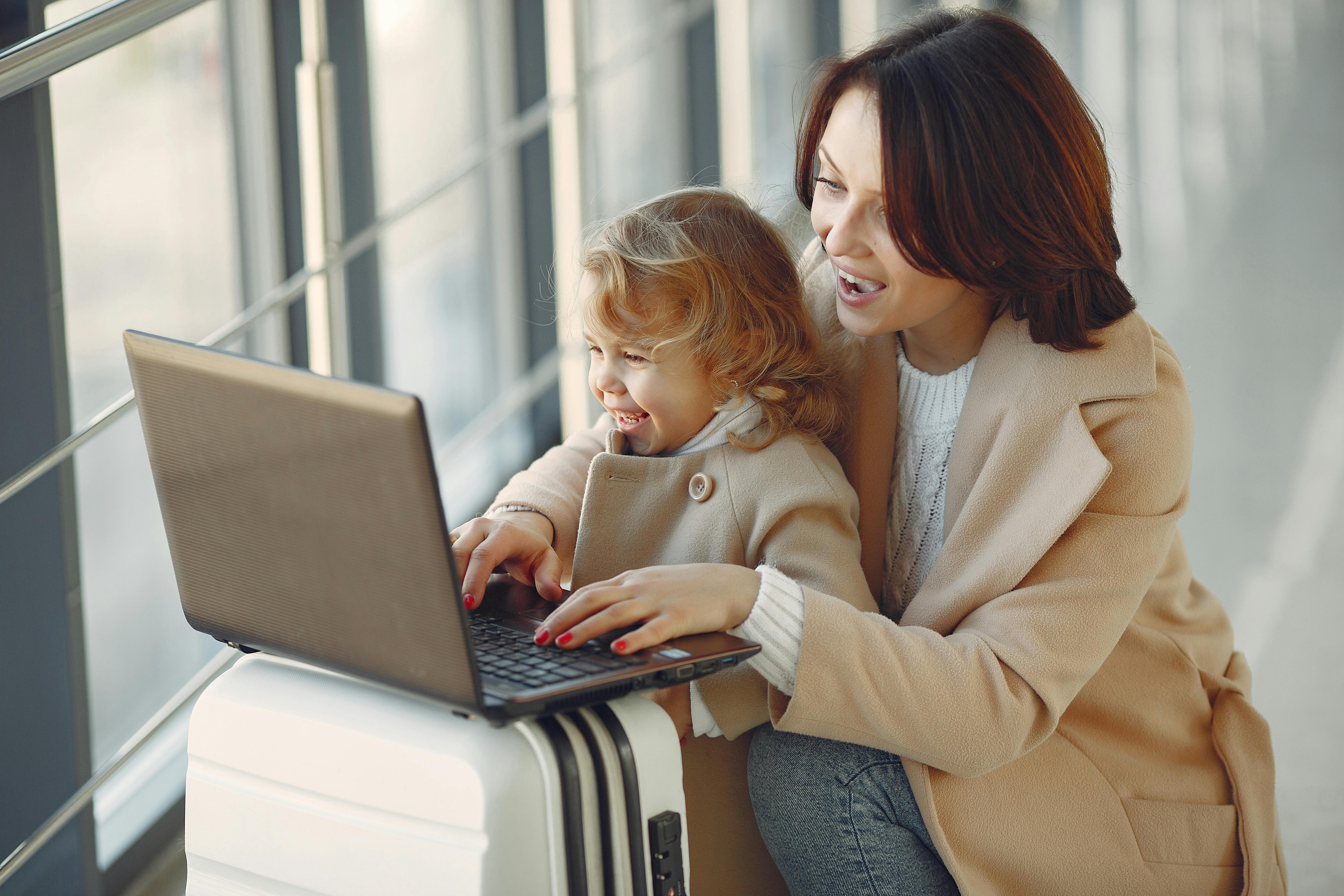 Família planejando viagem - Mãe e filha usando laptop para reservar passagens